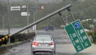 A car drives pass a collapsed traffic sign, toppled by strong winds of typhoon Meranti, as it slashes southern Taiwan on September 14, 2016.   AFP / SAM YEH