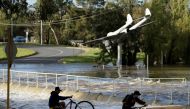 Boys bicycle out of floodwaters after heavy rains inundated the midwestern New South Wales town of Forbes, Australia, September 27, 2016. REUTERS/Jason Reed