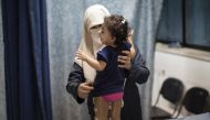 A woman supports her child as she tries to stand in prosthetic legs at Gaza's Artificial Limbs and Polio Centre (AFP Photo/Mahmud Hams)