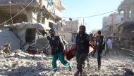 Syrian volunteers carry an injured person on a stretcher following Syrian government forces airstrikes on the rebel held neighbourhood of Heluk in Aleppo, on September 30, 2016. AFP / THAER MOHAMMED
