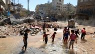 Children play with water from a burst water pipe at a site hit yesterday by an air strike in Aleppo's rebel-controlled al-Mashad neighbourhood, Syria, September 30, 2016. REUTERS/Abdalrhman Ismail
