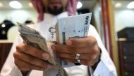 A man counts Saudi riyal banknotes at his jewelry shop in Tiba market in the capital Riyadh on October 3, 2016. / AFP / FAYEZ NURELDINE