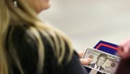 A woman holds fake money with Republican Presidential Candidate Donald Trump's face on it before the start of his rally at the Convention Center in Charlotte, North Carolina on October 14, 2016. / AFP / Logan Cyrus