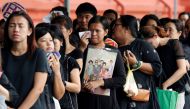 A mourner holds up a picture of Thailand's late King Bhumibol Adulyadej as she waits in line to pay respects to him outside the Grand Palace in Bangkok, Thailand, October 19, 2016. REUTERS/Chaiwat Subprasom