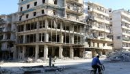 A man rides a bicycle near damaged buildings in the rebel held besieged al-Sukkari neighbourhood of Aleppo, Syria October 19, 2016. REUTERS/Abdalrhman Ismail
