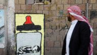 A man walks pass a graffiti by artist Thi Yazen AL-Alawy depicting a bottle of milk with a malnourished child inside along a street in Sanaa, Yemen, October 20, 2016. The graffiti is part of a campaign by several artists titled 