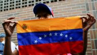 A woman holds a Venezuelan flag outside a validation center in Caracas, Venezuela, June 20, 2016.( REUTERS / Ivan Alvarado) 