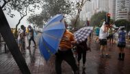 People use their umbrellas near a coastal barrier as Typhoon Haima makes landfall Hong Kong on October 21, 2016, during a typhoon signal eight warning.  AFP / ANTHONY WALLACE