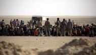 Syrian Democratic Forces stand guard as Iraqi refugees who fled Mosul, the last major Iraqi city under the control of the Islamic State (IS) group, due to clashes during the ongoing assault by the Iraqi government forces to retake the city, wait to enter 