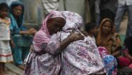 Family members comfort each other as they mourn the death of Salamat Maseh, a father of two who died after consuming locally-made toxic liquor in Karachi, Pakistan. (AKHTAR SOOMRO/REUTERS) 2013.