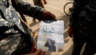 An Iraqi soldier shows a pamphlet which reads 