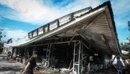 A police officer walks past a 7-11 convenience store in the Thai southern province of Pattani on November 3, 2016, after it was damaged in a bombing the night before. AFP / TUWAEDANIYA MERINGING