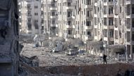 A member of the Syrian pro-government forces stands amid heavily damaged buildings in Aleppo's 1070 district on November 8, 2016, after troops seized it from rebel fighters.  AFP / GEORGES OURFALIAN
