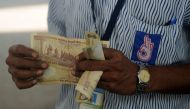 An Indian worker holds a stack of 500 Indian Rupee notes on the forecourt of a fuel station in Chennai on November 9, 2016. AFP / ARUN SANKAR
