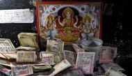 500 and 1000 Indian rupee banknotes are kept in front of an image of the Hindu deities at a cash counter inside a bank in Jammu. Reuters/Mukesh Gupta
