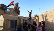 Children gather next to an Iraqi forces vehicle patrolling a street in the village of Jarif, some 45 kilometres south of Mosul, on November 12, 2016, after retaking it from Islamic State (IS) group jihadists. / AFP / SAFIN HAMED
