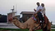 Iranian tourists ride a camel in Iran's southern resort island of Kish on November 1, 2016. Iranian investors are pouring money into Kish island in the Gulf, hoping its white sand beaches, coral reefs and more relaxed Islamic rules, could make it a major 