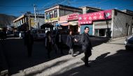 This picture taken on September 10, 2016 shows people walking down a street in Bayi district of the regional capital Lhasa, in China's Tibet Autonomous Region. The traditional teahouses and fashion boutiques of Bayi are the among the liveliest districts o