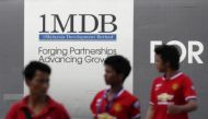 Men walk past a 1Malaysia Development Berhad (1MDB) billboard at the fund's flagship Tun Razak Exchange development in Kuala Lumpur March 1, 2015. REUTERS/Olivia Harris/File Photo