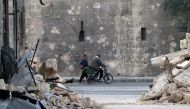 A man walks past a man riding a bike near the rubble of damaged buildings in the rebel held area of Old Aleppo, Syria November 14, 2016. REUTERS/Abdalrhman Ismail

