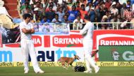 England's captain Alastair Cook (L) and spectators watch a dog which ran onto the field during the first day of the second Test cricket match between India and England at the Dr. Y.S. Rajasekhara Reddy ACA-VDCA Cricket Stadium in Vishakhapatnam on Novembe
