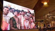 Indian mining tycoon, Gali Janardhan Reddy, (C) is seen on a big screen as he poses with his daughter Bramhani (2R) and son-in-law, Rajeev Reddy (2L) during their wedding at the Bangalore Palace Grounds in Bangalore. (AFP)
