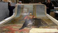 A picture taken in Saint Petersburg on November 17, 2016 shows restorers of the Stieglitz Art and Industry Academy displaying the portrait of Tsar Nicholas II by Ilya Galkin (1896) that was discovered beneath water-soluble paint on the back of the canvas 