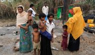 A family stands beside remains of a market which was set on fire, in Rohingya village outside Maungdaw, in Rakhine state, Myanmar October 27, 2016. REUTERS/Soe Zeya Tun
