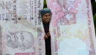 A man poses with replica prints of the demonetised 500 and 1000 rupee notes as part of a street art exhibition in Mumbai on November 20, 2016. (AFP / Indranil MUKHERJEE)