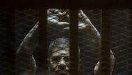 A file picture taken on June 2, 2015 shows ousted Egyptian president Mohamed Morsi gesturing from the defendants cage as he attends his trial at the police academy on the outskirts of the capital Cairo. / AFP.