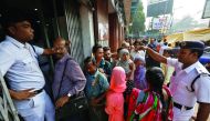 A police officer speaking with people as they queue outside a bank in Kolkata, yesterday.
