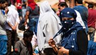REPRESENTATIVE IMAGE: A woman pulls a corner of her headscarf as she stands with refugees and migrants upon their arrival with a boat near the village of Finokalia in the southern Greek island of Crete on May 31, 2016 (AFP)