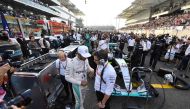 Mercedes AMG Petronas F1 Team's British driver Lewis Hamilton (C-L) talks to a member of his team ahead of the start of the Abu Dhabi Formula One Grand Prix at the Yas Marina circuit on November 27, 2016. / AFP / Andrej ISAKOVIC
