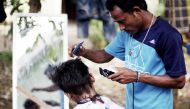 A Rohingya refugee man cuts the hair of a kid at a temporary shelter in Beras Pati after arrived from Aceh Shelter, in Medan of North Sumatra, Indonesia on November 25, 2016. About 164 Rohingyas are accommodated by the Indonesian Government arrived in Ber