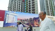People walking past a billboard advertising a new housing complex outside a construction site in Beijing.