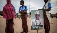 School girls, supporting the Gambian incumbent president Yahya Jammeh, stand by a placard picturing him as the y wait for the start of an electoral meeting in Schur Alagie on November 28, 2016. AFP / MARCO LONGARI