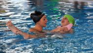 A Bosnian swim coach (L) swims with a disabled child during a training session on November 22, 2016, at Sarajevo's Olympic Swimming Pool facility. AFP / ELVIS BARUKCIC