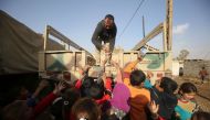 An Iraqi soldier distributes drinks and food to Iraqi children, displaced from the outskirts of the city of Tal Afar, arrive on trucks on December 3, 2016 in the village of Tall al-Zarka after their families fled the ongoing fighting between Iraqi forces 