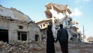 Kefa Jawish (L) and her husband Tajeddin Ahmed look a destroyed building in the Aleppo's northeastern Haydariya neighbourhood as they head to check their house for the first time in four years on December 4, 2016. 
AFP / Youssef KARWASHAN 