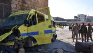 Syrian pro-government forces stand next to the wreckage of an ambulance outside a makeshift hospital which was used by rebel fighters in Aleppo's al-Sakhur neighbourhood, on December 6, 2016, a few days after the area was retaken by the government troops.