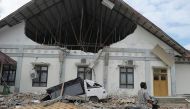 TOPSHOT - a man rides past a district hospital which was damaged after an earthquake in Pidie Jaya, Aceh province on December 7, 2016. At least 52 people were killed and hundreds injured on December 7 after a strong earthquake struck Indonesia's Aceh prov