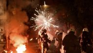 Police officers look on as a firework thrown by protesters explodes in front of them in the central district of Exarchia in Athens, on December 6, 2016, following a commemorative rally marking the eighth anniversary of the killing of teenager Alexandros G