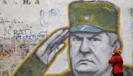 A woman walks past graffiti of Bosnian Serb wartime general Ratko Mladic in a suburb of Belgrade, Serbia, May 27, 2011. REUTERS/Stoyan Nenov