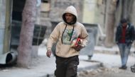 A man carries food as he walks along a street in a rebel-held besieged area of Aleppo, Syria December 10, 2016. REUTERS/Abdalrhman Ismail
