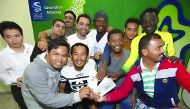 Barcelona legend Xavi Hernandez poses for a photograph with some of the workers who received tickets for tomorrow's Barcelona vs Al Ahli match during his surprise visit to the Labour City. 