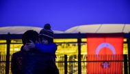 A man holds his child next to Turkish national flag during a demonstration on December 11, 2016 a day after twin bombings near the home stadium of Besiktas football club. AFP / YASIN AKGUL
