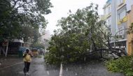 An Indian man walks along a street covered with debris and fallen trees in Chennai as Cyclone Vardah approaches the Indian coast on December 12, 2016.  AFP / STR
