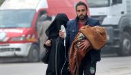 A man carries a child with an IV drip as he flees deeper into the remaining rebel-held areas of Aleppo, Syria December 12, 2016. REUTERS/Abdalrhman Ismail TPX IMAGES OF THE DAY
