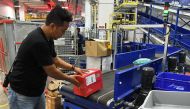This photograph taken on December 5, 2016 shows a worker placing inbound parcels on a conveyor belt for coding at the sorting section of the Singapore Post (SingPost) ecommerce logistics centre in Singapore. AFP / Roslan RAHMAN 