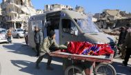 A man pushes a cart with a woman lying on it as vehicles wait to evacuate people from a rebel-held sector of eastern Aleppo, Syria December 15, 2016. REUTERS/Abdalrhman Ismail
